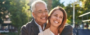 Smiling older man and woman embracing outdoors