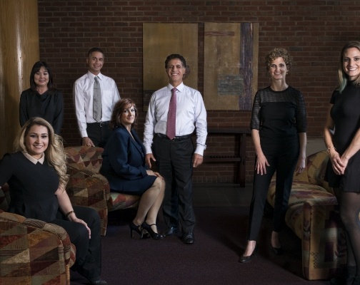 Brookline dental team members in formal attire in room with brick wall