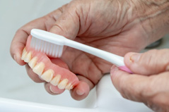 Close up of patient brushing their denture