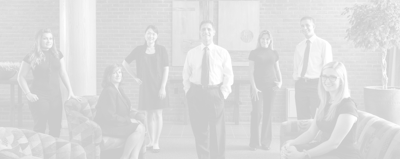 Boston Smile Center dental team wearing formal attire in room with brick wall