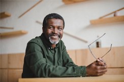 man smiling while holding glasses 