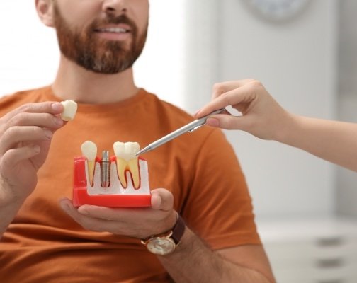 Dentist showing a patient a model of a dental implant