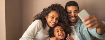 Mother father and young child taking group selfie after dental services in Brookline