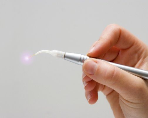 Hand holding a soft tissue dental laser