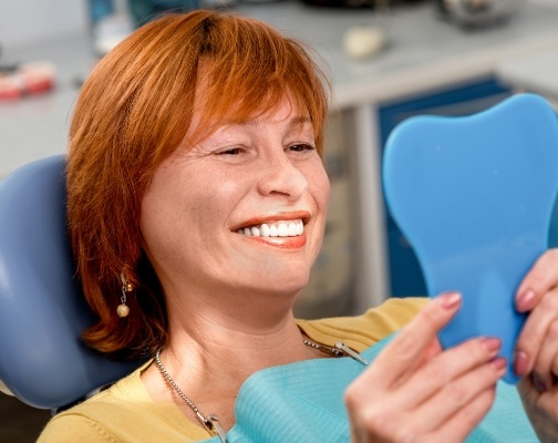 Redheaded woman admiring her smile in mirror