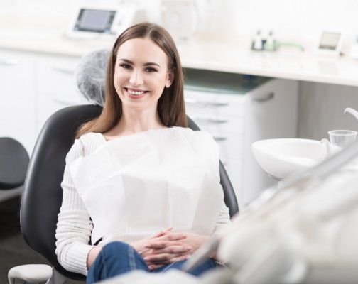 Smiling Brookline dental patient sitting with her hands in her lap