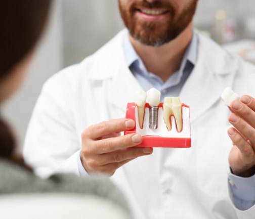 Dentist showing a model of a dental implant to a patient