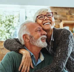 Senior man and woman hugging in their home