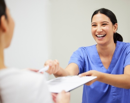 Dental team member accepting dental insurance card from a patient