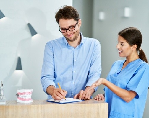 Dental team member showing a patient where to sign on clipboard