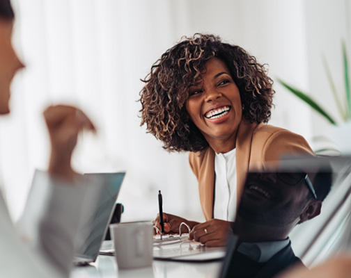 Woman smiling while taking notes during meeting