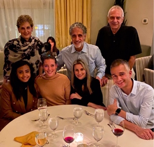 Doctor Sasson sitting at restaurant table with several other dental team members