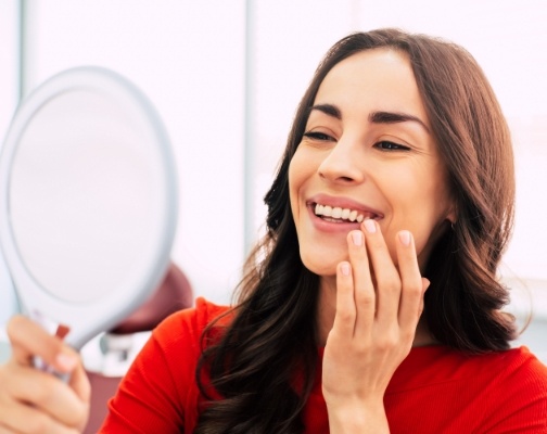 Young woman in dental chair admiring her smile in a mirror