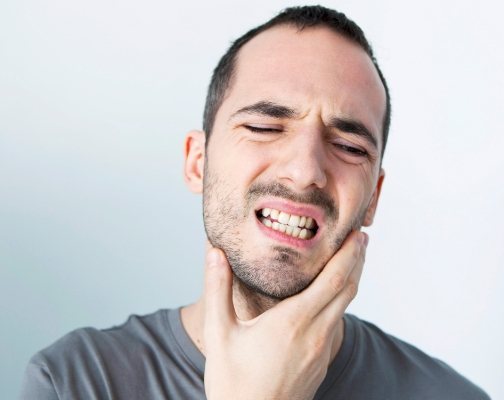 Man touching the side of his jaw in pain