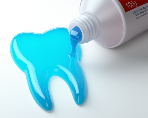 Blue toothpaste spilling out of tube in the shape of a tooth