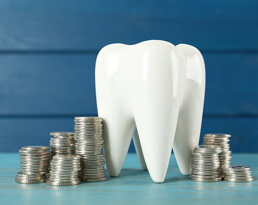 A tooth model and coins against a blue background 