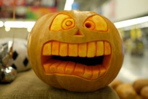 orange pumpkin with a scared face carved into it 