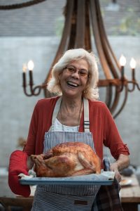 Older woman with dentures holding Thanksgiving turkey