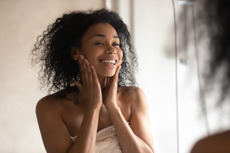 person with straight teeth smiling at reflection