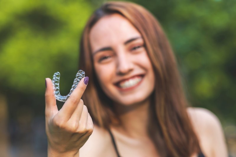 young woman holding her Invisalign aligner
