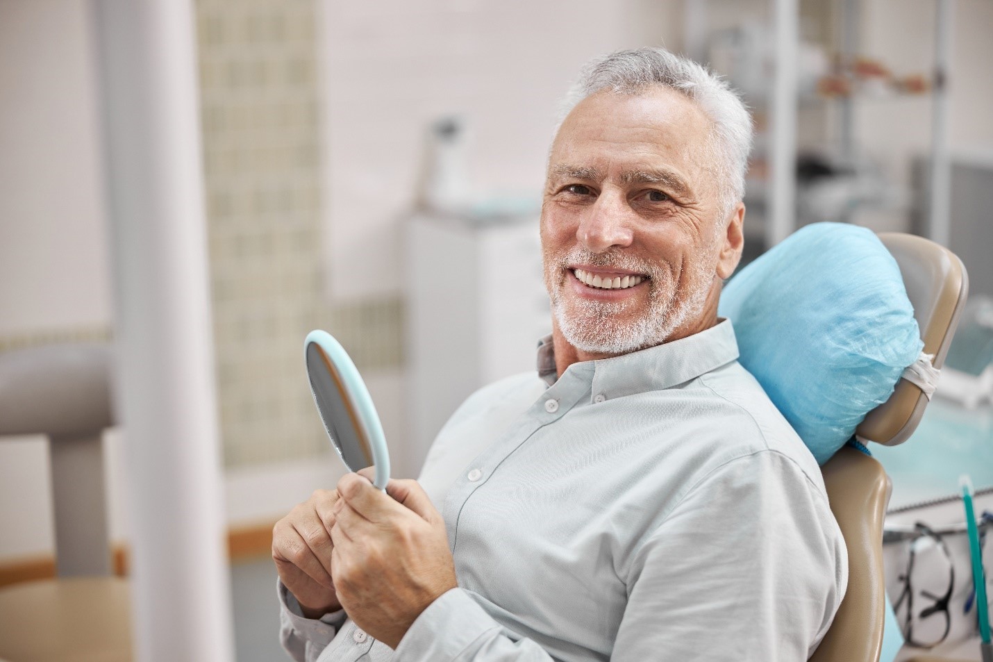 older-man-smiling-at-dentist-and-holding-mirror