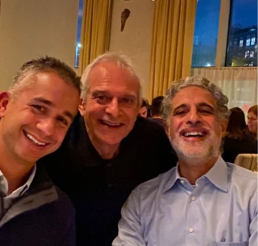 Dr. Sasson with two colleagues at a formal event with Boston cityscape visible through windows
