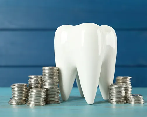 A tooth model and coins against a blue background