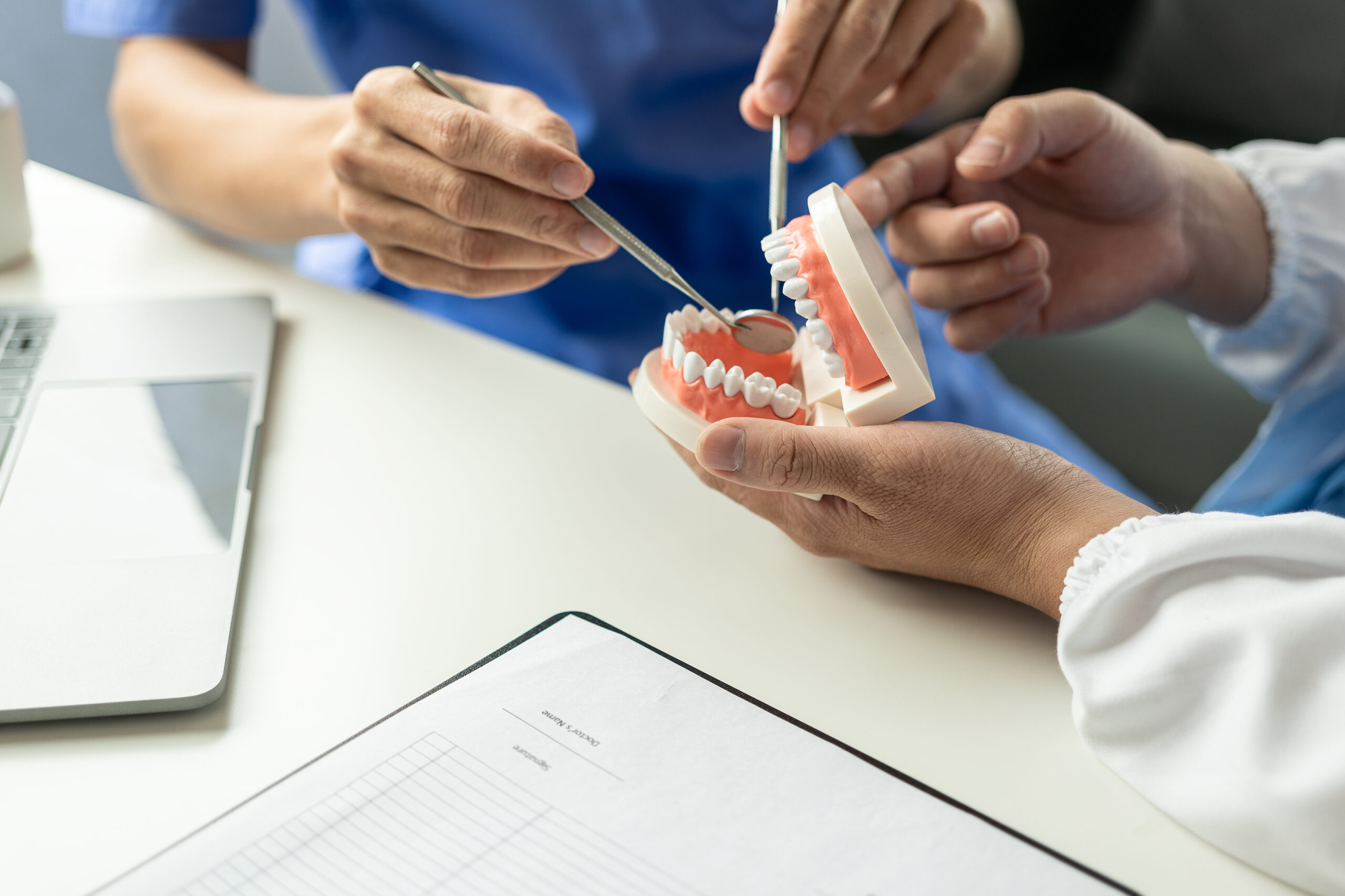 Dentist holding a tooth model while consulting with a patient about restorative dental options